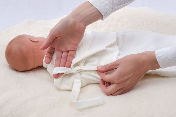 Baby lagern mit Puckband und Pucktuch aus Bio Jersey Pucken mit Tuch und Wickelband aus ökologischem Jersey auf weicher angenehmer Babydecke aus Püsch